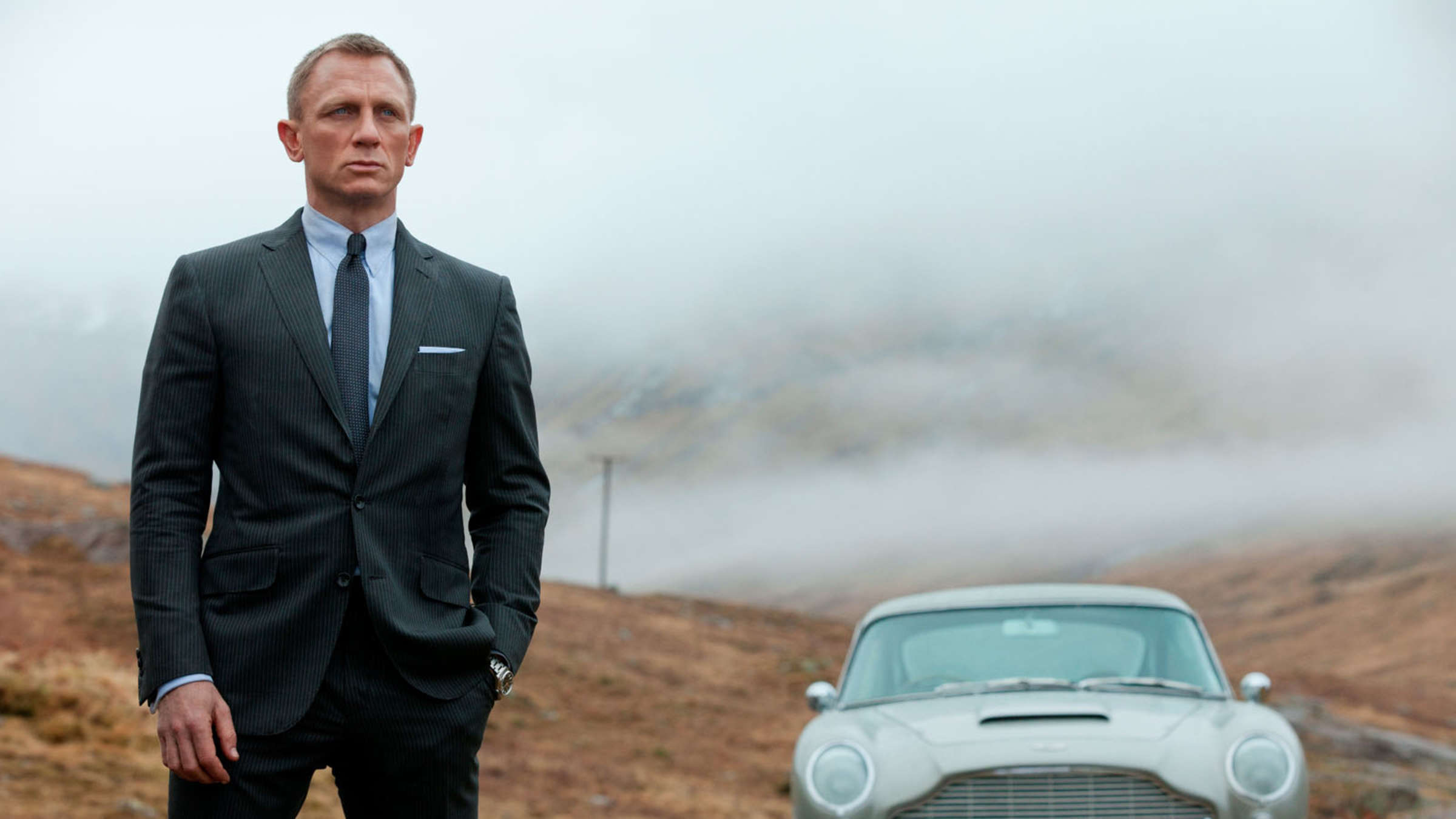 Daniel Craig jako James Bond vedle svého klasického Astona Martina v Skyfall