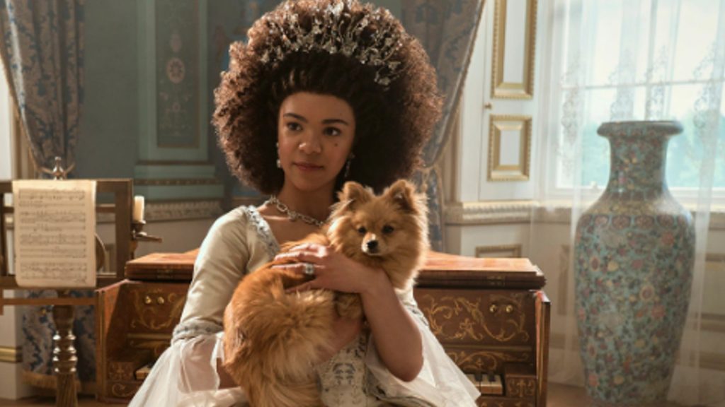 Unga drottning Charlotte håller sin hund i Queen Charlotte: En Bridgerton Story